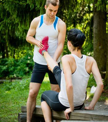 A runner helps another runner with leg cramps by stretching their leg