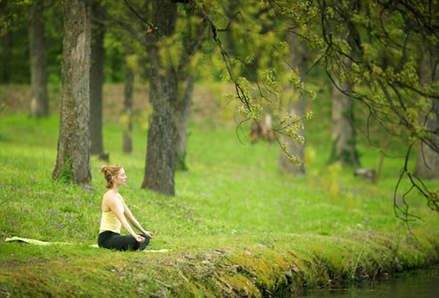 Woman meditating on the bank of a river